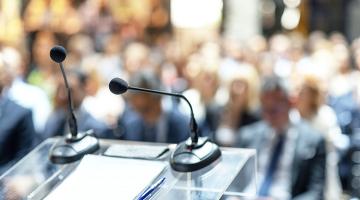 a microphone on a lectern at the front of a large meeting